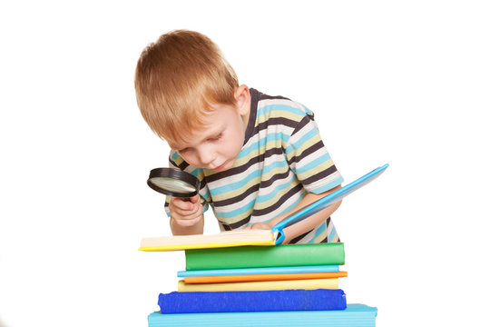Little boy reading book with magnifying glass