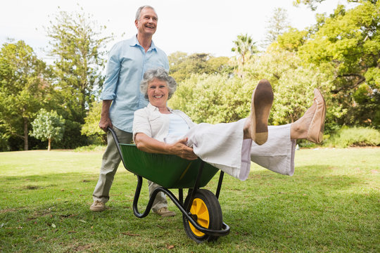Happy man pushing his laughing wife in a wheelbarrow