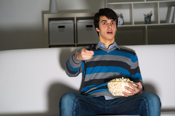 young man watching television with popcorn