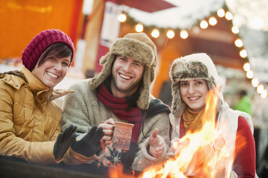Austria, Salzburg, Man and women by fire at Christmas market, smiling
