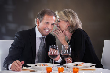 Cheerful Woman Whispering In Man's Ear