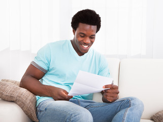 Happy Young Man Looking At Paper