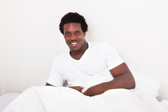 Young Man Sitting On Bed