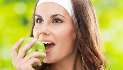 Woman in fitness wear with apple, outdoors