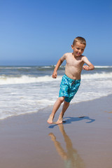 Fototapeta na wymiar Boy running and smiling at beach