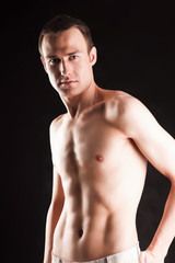 Fototapeta premium Portrait of a naked muscular man, isolated on black background