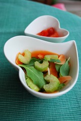Vegetables salad in two heart shape bowls on green background