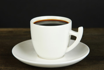 Cup of coffee on wooden table on black background