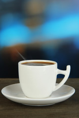 Cup of coffee on wooden table on bright background