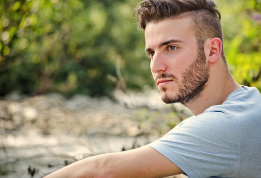 Portrait of handsome young man in white t-shirt in nature