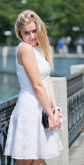 Beautiful young blond woman in a white dress outdoors