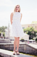 Obraz premium Beautiful young blond woman in a white dress outdoors
