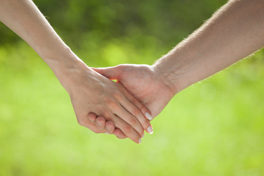 Hands of man and woman holding together