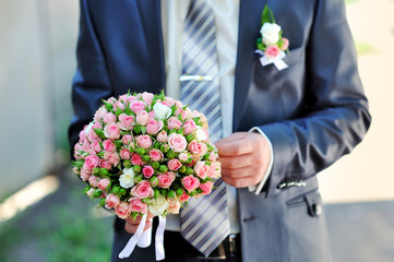 groom is holding a wedding bouquet