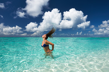 Fototapeta na wymiar Woman splashing water with hair in the ocean