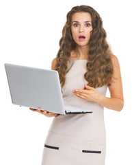 Surprised young woman pointing on laptop