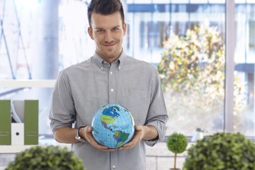 Young man holding globe smiling