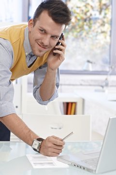 Young man talking on mobile in office, smiling