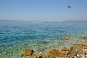 Paraglider on the sky dragged by boat, under amazing beach
