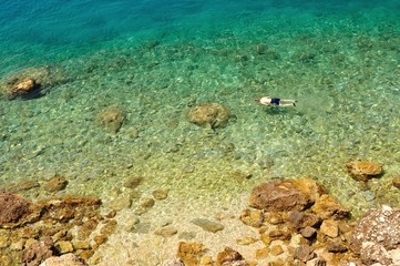 View on dalmatian rocky beach in Croatia with swimming man