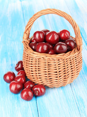Cherry berries in wicker basket on wooden table close-up