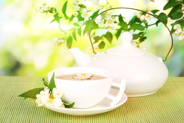Cup of tea with jasmine, on bamboo mat, on bright background