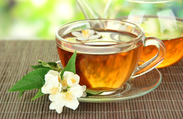 Cup of tea with jasmine, on bamboo mat, on bright background