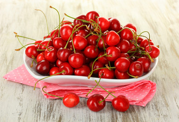 Cherry berries on plate on wooden table close up