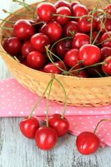 Cherry berries in wicker basket on wooden table close up