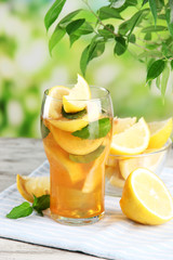 Iced tea with lemon and mint on wooden table, outdoors