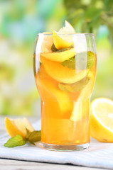 Iced tea with lemon and mint on wooden table, outdoors