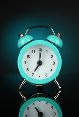 Blue alarm clock on dark blue background