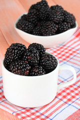 Sweet blackberries in cup on table close-up