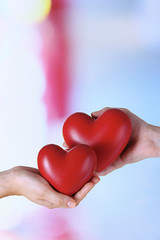 Hearts in hands on light background