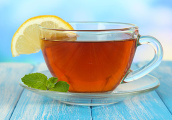 Cup of tea with lemon on table on blue background