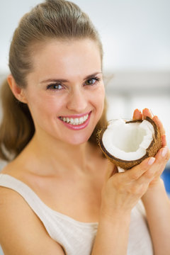 Portrait of happy young woman showing coconut