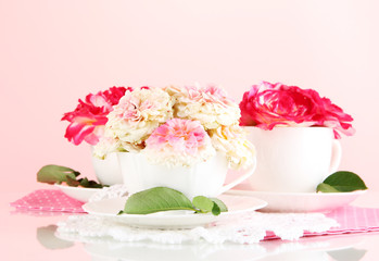 Fototapeta na wymiar Roses in cups on napkins on pink background