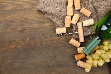 Bottle of wine, grapes and corks on wooden background