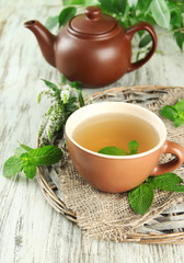 Teapot and cup of herbal tea with fresh mint flowers