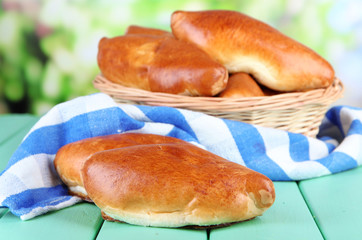 Fresh baked pasties in wicker basket, on bright background