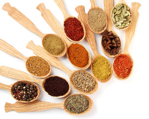 Assortment of spices in wooden spoons, isolated on white