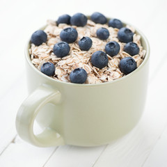 Cup of cereals with fresh blueberries, studio shot