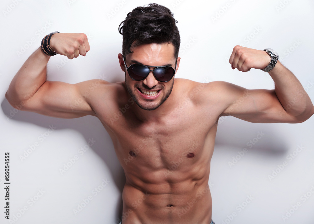 Wall mural topless young man showing you his biceps