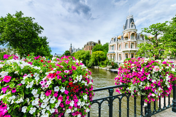 Canal in Amsterdam with flowers on a bridge - obrazy, fototapety, plakaty
