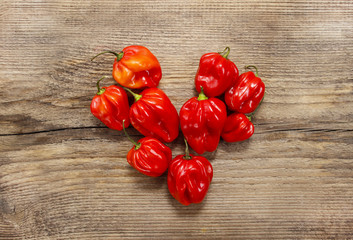 Red peppers in heart shape on old wooden table. Copy space.