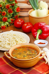 Pot of tomato soup and fresh vegetables on old wooden table