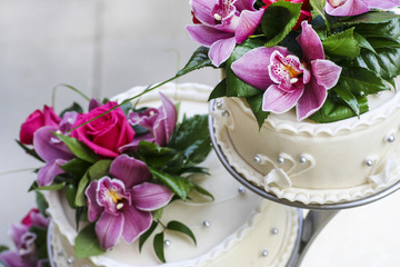 Obraz na płótnie Canvas Tort weselny ozdobiony pięknymi purpurowe i różowe storczyki