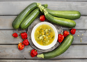 Top view of vegetable soup on wooden table. Raw vegetables aroun