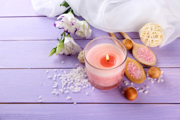 Beautiful pink candle with flowers on purple wooden background