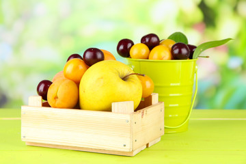 Bright summer fruits in pail and wooden box